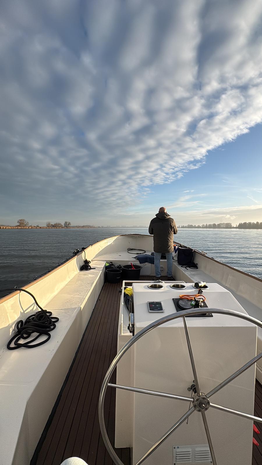 Onze schipper aan het roer, open water met dramatische lucht